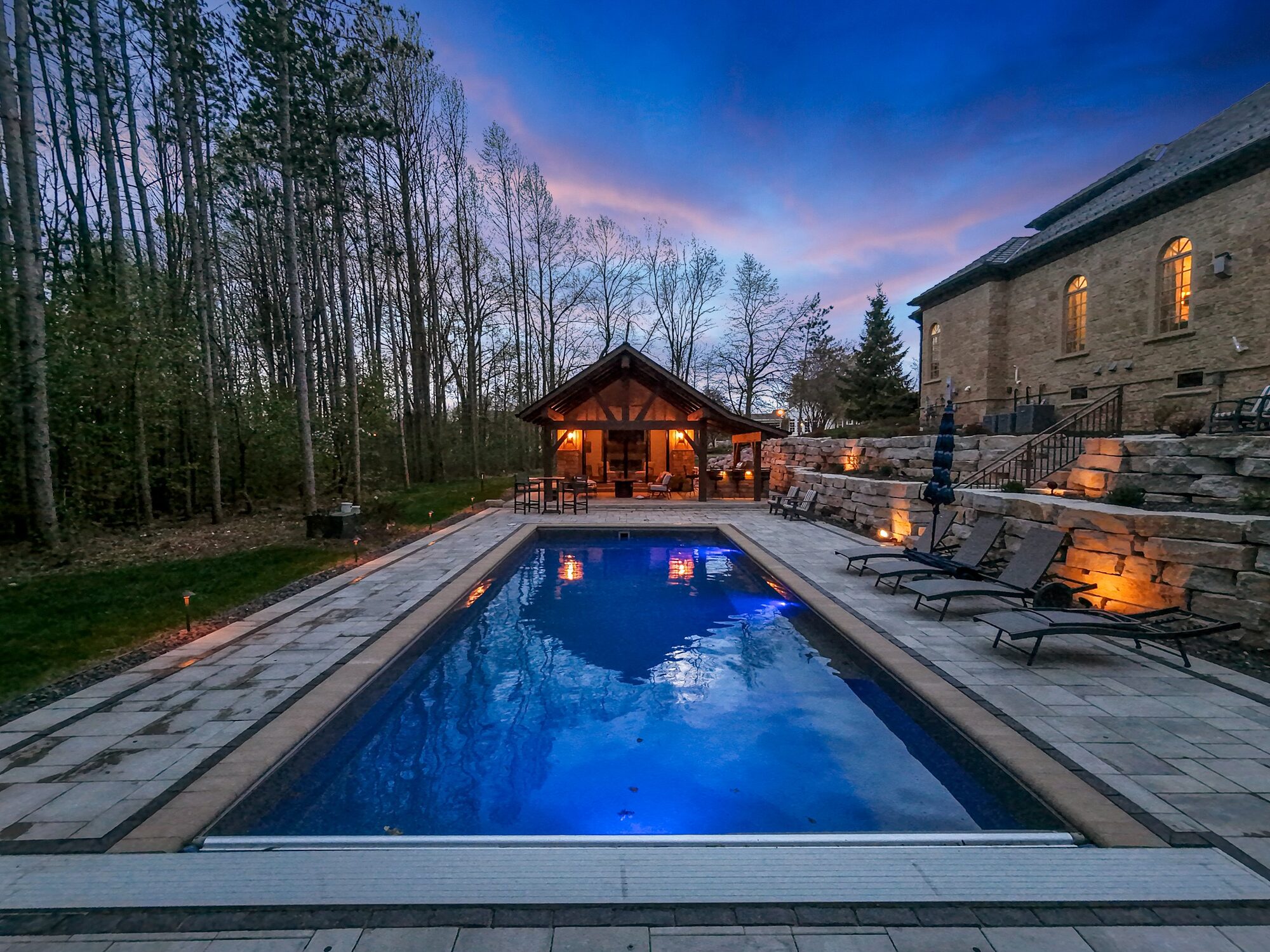 Pool and pool house illuminated at dusk