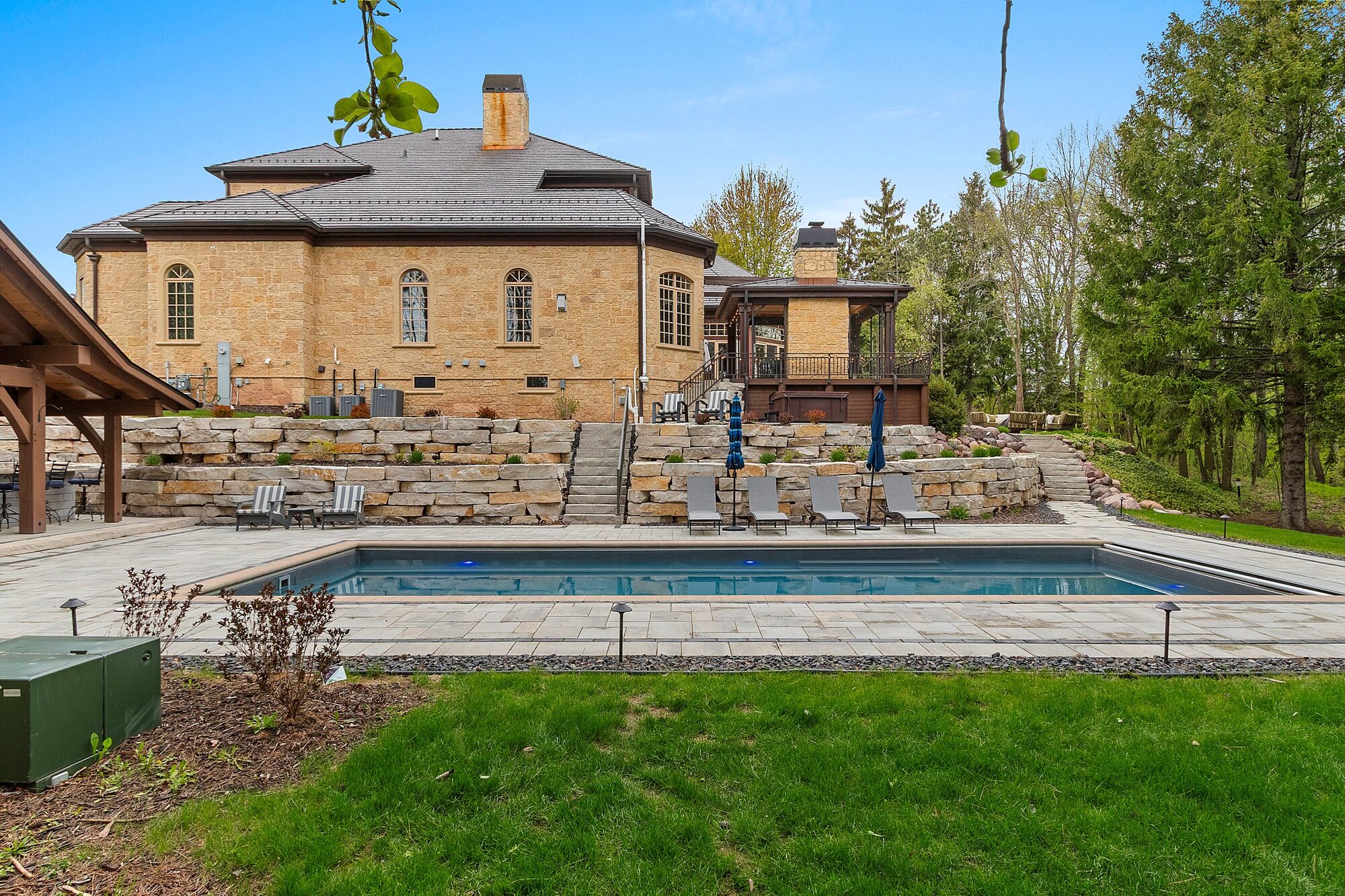 Inground pool with stone retaining walls and pool house